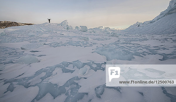 Ein Mann steht auf einem Eisberg im Rossmeer in der Antarktis.