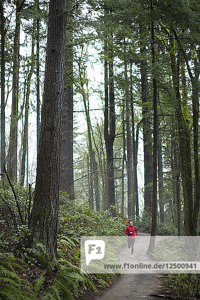 A woman running a trail in Forest Park. Portland  Oregon.
