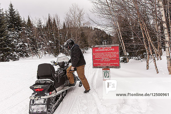 Mann steigt in der Nähe der kanadischen Grenze auf ein Schneemobil