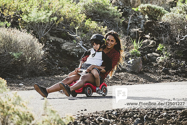 Eine Frau mit ihrem Sohn genießt die Fahrt auf einem Spielzeugauto