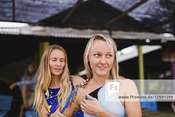 Eine Frau deckt die Tattoos ihrer Freundin mit Klebeband ab  um sie vor der Sonne zu schützen