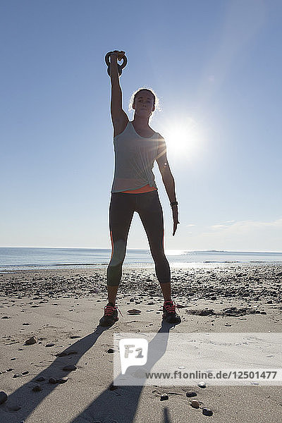 Frau stehend mit Kettlebell tun Übung am Strand