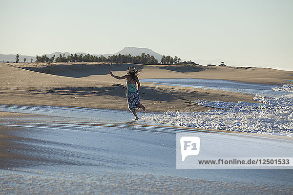 Eine erwachsene Frau flirtet mit den Wellen in Todos Santos in Mexiko