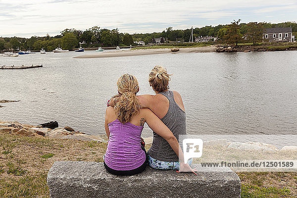 Zwei Frauen  die sich umarmen und auf das Wasser schauen.