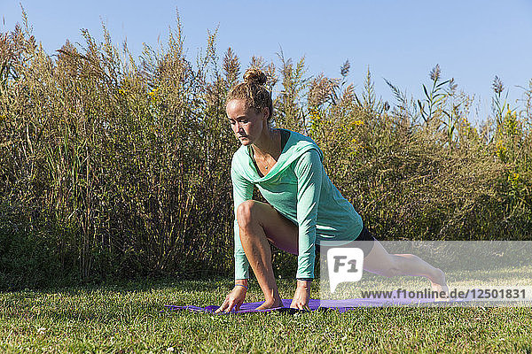 Junge Frau macht Yoga auf Gras
