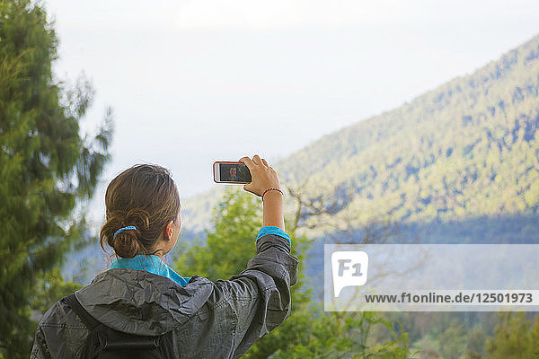 Weiblicher Wanderer  der mit seinem Smartphone ein Bild vom Berg macht