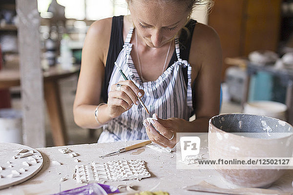 Künstlerische Frau arbeitet an einer Form in einer Keramikwerkstatt