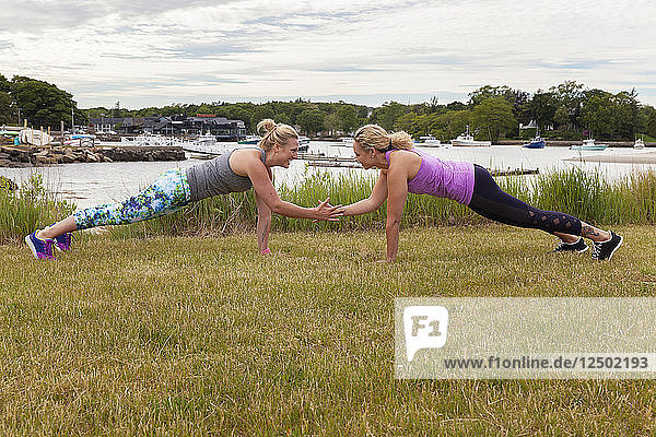 Zwei Frauen beim Partnertraining Push-up Plank High-Five