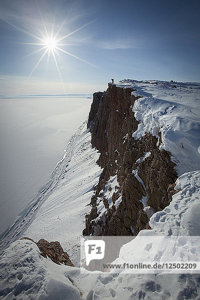 Long Exposure Of Person Standing On Snowy Cliff In Arctic Bay