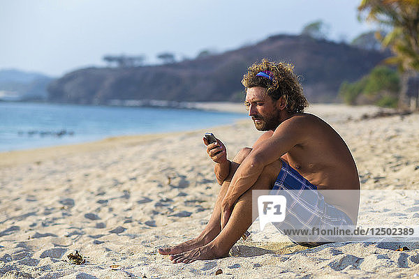 Mann telefoniert am Strand.West Sumbawa.Indonesien.