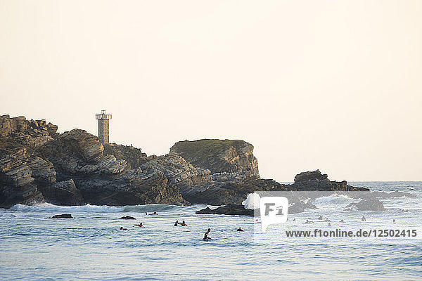 Evening light paints the lighthouse of Punta Zicatela  while many surfers pack the lineup in Puerto Escondido  Mexico.