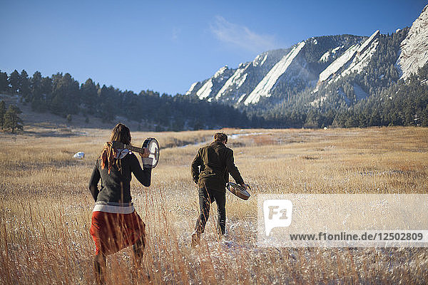 Die Musiker Ian Van Ornum (rechts) und Dani Aubert wandern mit ihrer Mandoline und ihrem Banjo unterhalb der Flatirons in Chautauqua  Boulder  Colorado.