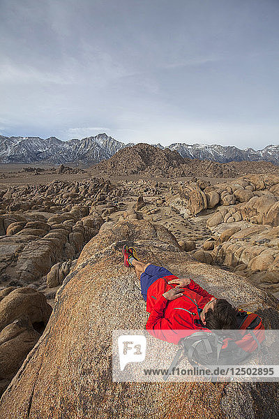 Mann entspannt sich auf einem Felsen in den Alabama Hills am Fuße der Sierra Nevada