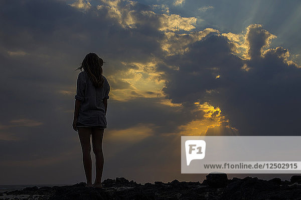 Woman looks at sunset in the ocean.West Sumbawa.Indonesia.