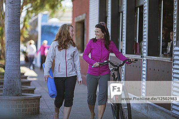 Two Women With Bicycle Walking On Footpath Of Encinitas  California