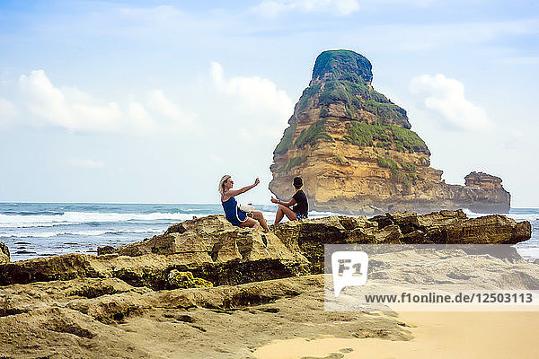 Zwei Frauen sitzen auf Felsen an der Küste