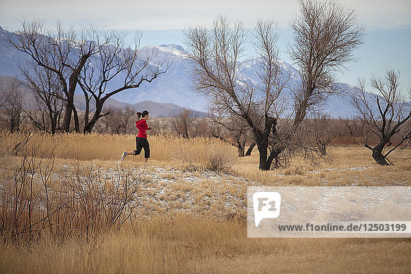 Adult woman running in savannah valley of Sierra Nevada Mountains