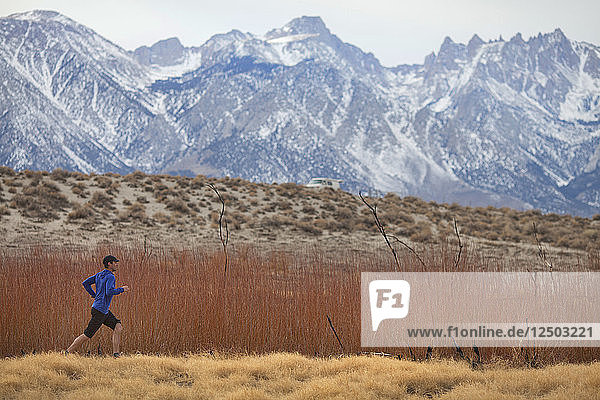Adult man running in savannah valley of Sierra Nevada Mountains