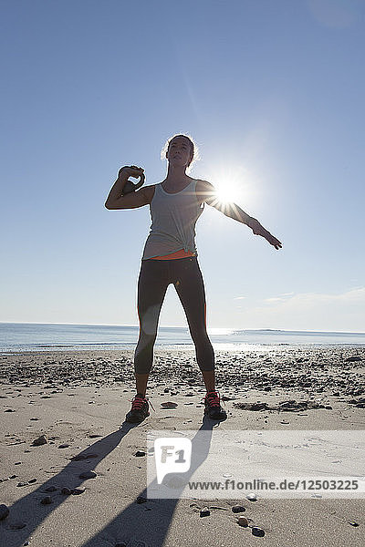 Woman Doing Exercise On Beach With Kettlebell