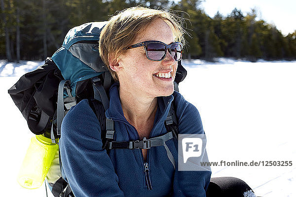 Eine Frau macht beim Schneeschuhwandern über den zugefrorenen Daicey Pond im Baxter State Park  Maine  eine Pause.
