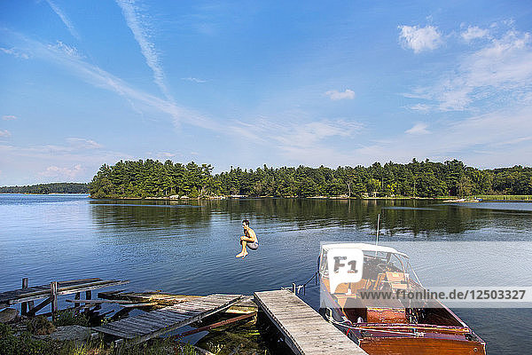 A Young Man Leaps Off A Dock Into The Calm Waters Of The Saint Lawrence River