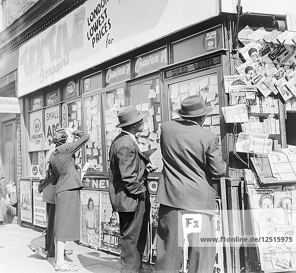 Betrachtung von Wohnungsanzeigen und Stellenausschreibungen in einem Kioskfenster  um 1955. Künstler: Henry Grant
