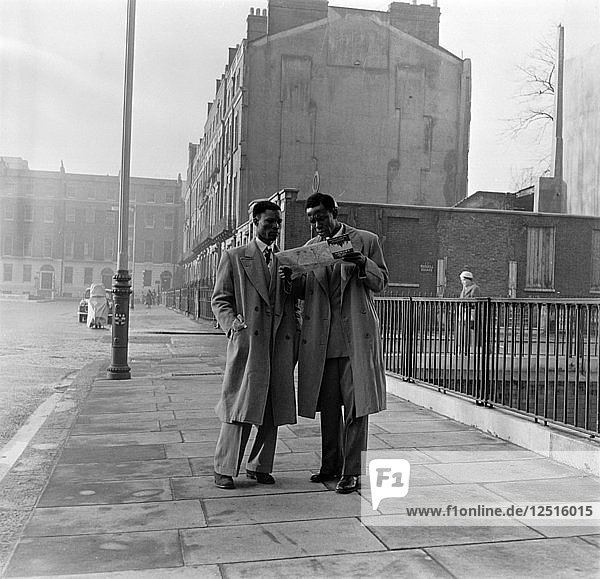Zwei afro-karibische Männer lesen auf der Straße eine Karte  London  (um 1950). Künstler: Henry Grant