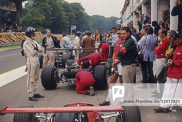 Graham Hill sieht Mechanikern bei der Arbeit an einem Auto zu  Großer Preis von Frankreich  Rouen  1968. Künstler: Unbekannt