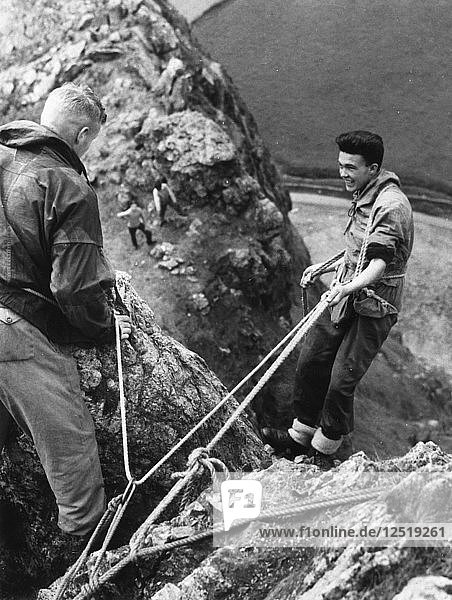 Boy about to start descent of rock face  Outward Bound School  Eskdale  Cumbria 1950. Artist: Unknown