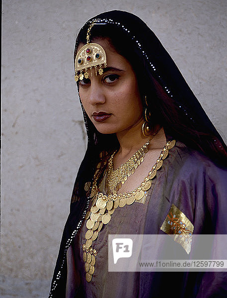 A woman wearing impressive gold jewellery and traditional costume.