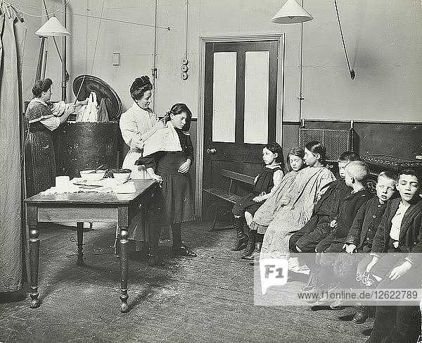 Krankenschwester schneidet Kindern die verunreinigten Haare  Finch Street Cleansing Station  London  1911. Künstler: Unbekannt.