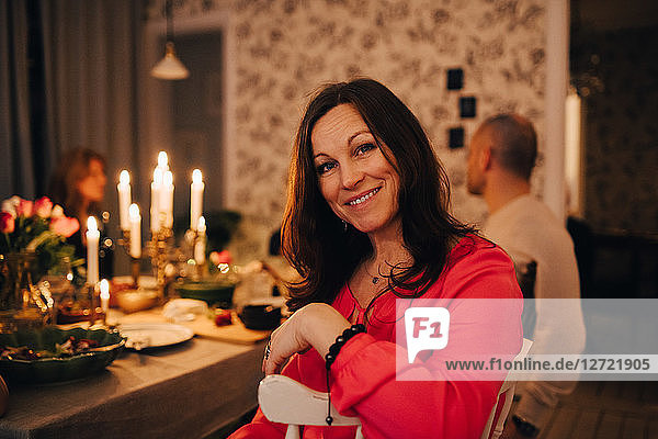 Portrait of smiling woman sitting with friends at dinner party