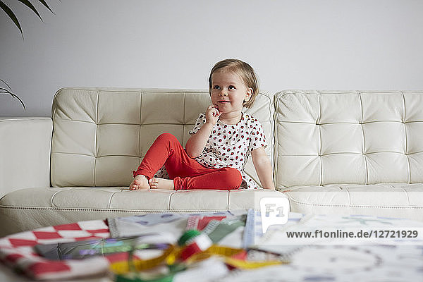 Thoughtful girl sitting on sofa at home