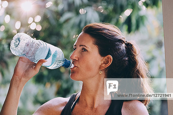 Mature woman drinking water from bottle at beach