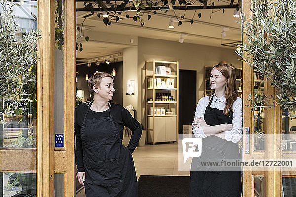Smiling female owners standing at doorway of store