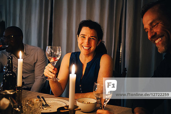 Happy woman enjoying dinner with male friends in party at home