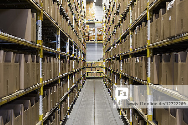 Empty narrow aisle amidst racks at warehouse