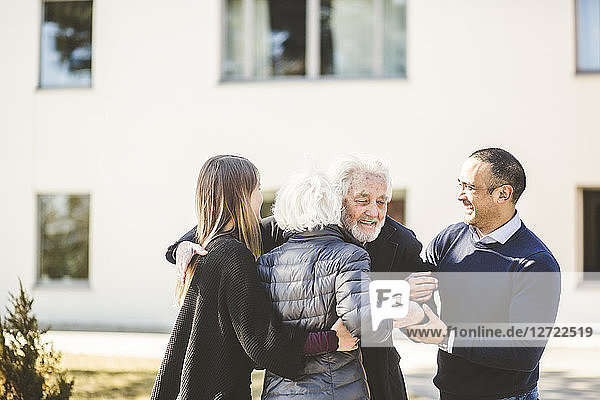 Happy multi-generation family embracing outside nursing home