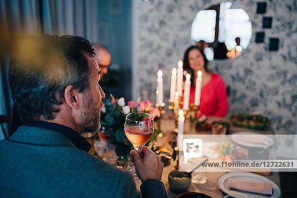 Mature man having wine while sitting with friends at dinner party