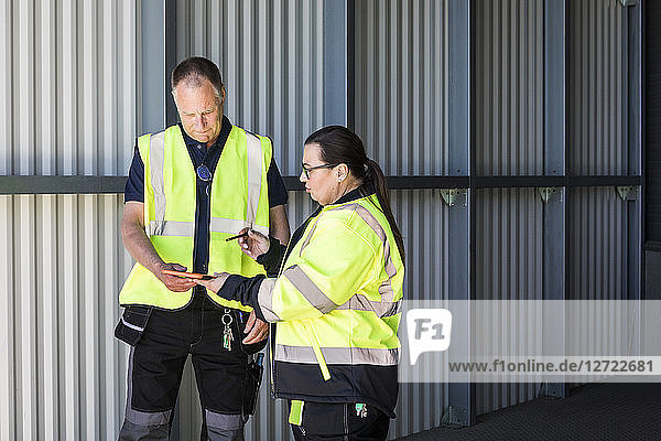 Warehouse workers discussing over digital tablet while standing at entrance