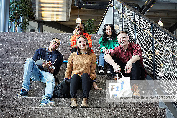 Portrait of smiling students sitting on steps in university