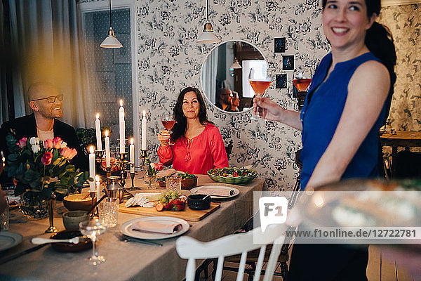 Woman enjoying drinks with friends at dining table in party