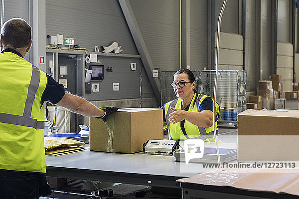 Coworkers packing merchandise on desk at warehouse