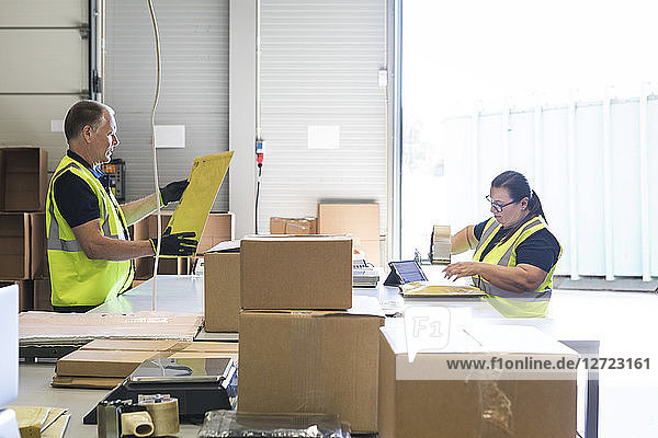 Coworkers packing merchandise on desk at distribution warehouse