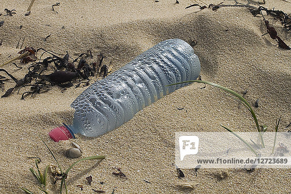 Nahaufnahme einer am Strand zurückgelassenen Plastikflasche