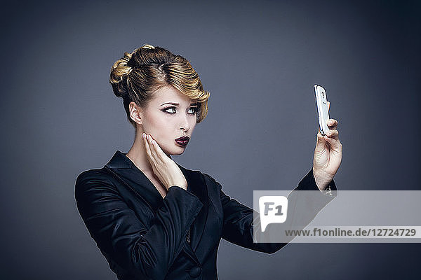 Porträt einer jungen Frau im Profil  die ein Foto mit ihrem Mobiltelefon macht