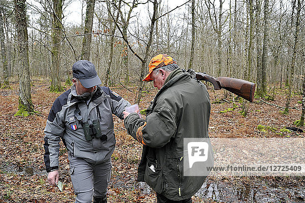 Frankreich  Jagd und Sicherheit  Beamter der französischen Umweltpolitik bei der Kontrolle eines Jägers während einer Jagd im Departement Loire-Atlantique.