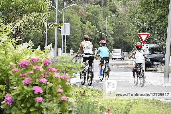 Frankreich  Pyla sur mer  Boulevard des Ozeans  Fahrradweg  eine Mutter und ihre zwei Kinder mit dem Fahrrad  Vorfahrt gewähren Schild  Grün rundherum /