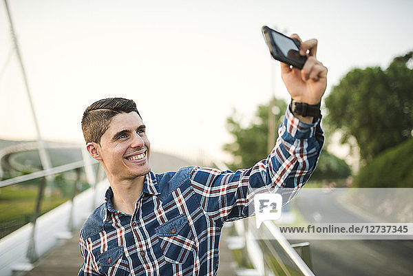 Smiling young man taking a selfie outdoors