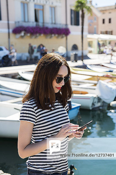Italy  Bardolino  Lake Garda  young woman using cell phone